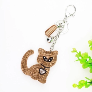 Close-up of sparkling cat keychain with brown rhinestones, suede tassel and silver bell