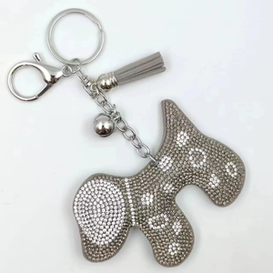 Détail d'un porte-clés chien gris argenté avec strass, clochette et pompon en velours