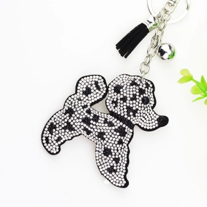 Détail du porte-clés chien à strass avec pois noirs, pompon et clochette argentée