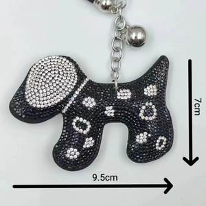 Détail du porte-clés chien noir avec motif floral en strass et clochette argentée