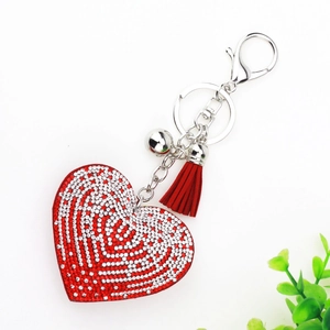 Détail d'un porte-clés cœur en strass rouge avec pompon en daim et fermoir argenté