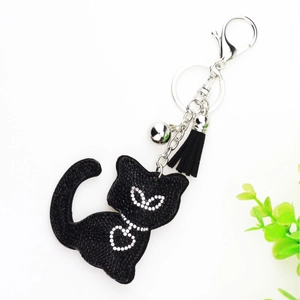 Detail of black cat keychain with rhinestones, heart bowtie, bell and tassel charm