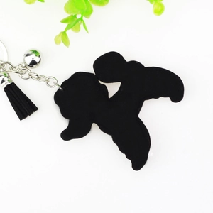 Détail d'un porte-clés teddy en velours noir avec clochette et pompon à franges chic