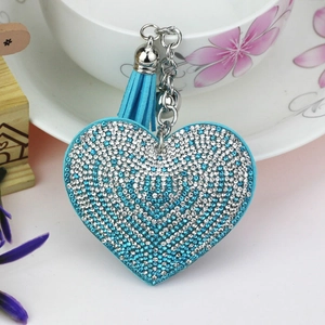 Détail du porte-clés cœur en strass bleu dégradé avec pompon en daim sur une tasse