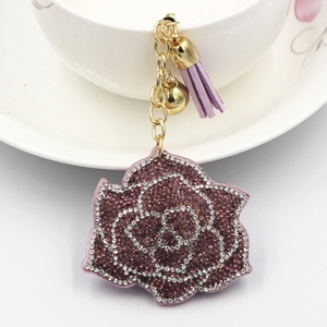 Detailed close-up of a purple rhinestone rose keychain with gold bell and leather tassel