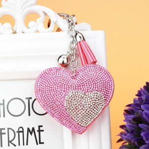 Dettaglio del portachiavi a cuore con strass rosa, nappa in pelle e un piccolo campanello