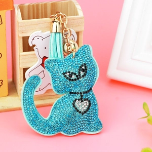 Close-up of sky blue rhinestone cat keychain with golden chain and tassel on pink background
