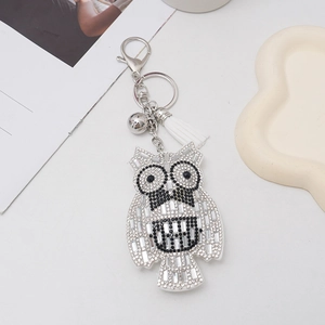 Detail of owl keychain with sparkling rhinestones, silver bell and white tassel charm