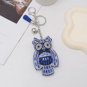 Detailed view of blue and white owl rhinestone keychain with fiber tassel and silver bell