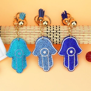 Detailed view of three Hamsa Hand charms featuring blue rhinestones and fabric tassels