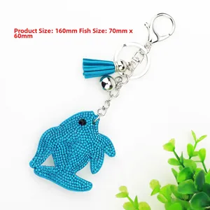 Detail view of a blue rhinestone dolphin keychain with leather tassel and silver bell charms