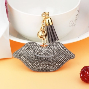 Close-up of glittery rhinestone lip keychain with grey leather tassel and gold chain