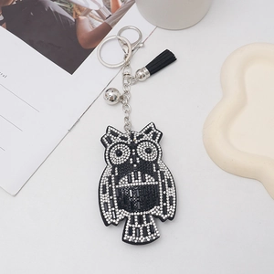 Close-up of rhinestone owl keychain with silver ring, small bell and black tassel detail