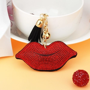 Detailed view of red rhinestone lips charm with black tassel and golden hardware for bags