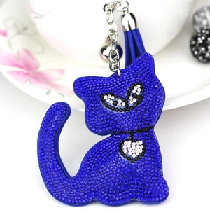 Blue rhinestone cat keychain with elegant tassel and silver bell on a ceramic plate