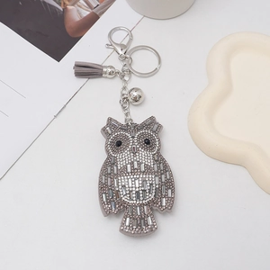 Detailed view of rhinestone owl keychain with grey suede tassel and silver metal hardware