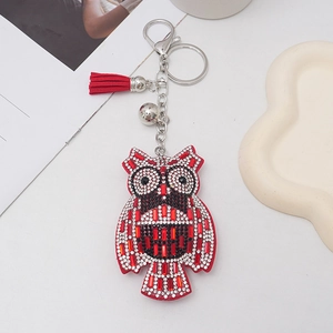 Detail of owl keychain with red and white rhinestones, silver bell, and red tassel