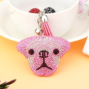 Porte-clés chien en strass rose avec pompon en daim et clochette sur une tasse blanche