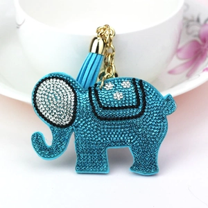 Sparkling blue elephant keychain with rhinestones and matching leather tassel on a white cup