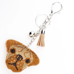 Détail du porte-clés chien avec strass marron et or, gland en cuir et cloche argentée