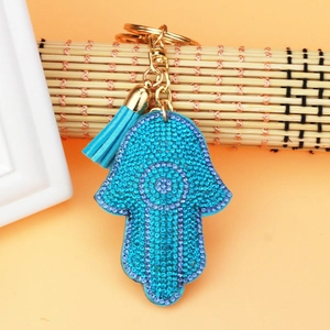 Detailed close-up of a Hamsa hand keychain with purple rhinestones and blue tassel detail