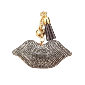 Lip-shaped keychain with dark grey rhinestones and elegant gold tassels on white background