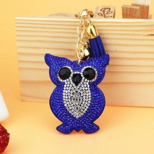 Detail of owl keychain with blue rhinestones, golden bell and deep blue tassel decor