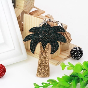 Detail of palm tree keychain featuring green rhinestones, brown suede, and a silk tassel