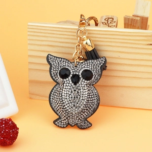 Close-up of sparkling owl keychain with black tassel and golden hardware detail