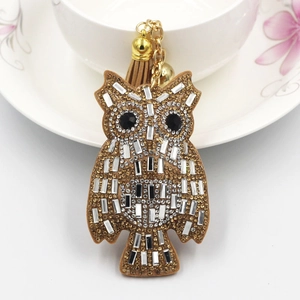 Close-up of owl keychain featuring sparkling gold rhinestones and leather tassel detail