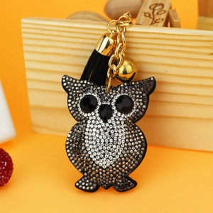 Detail of owl keychain with sparkling rhinestones, black tassel, and gold bell accent