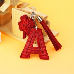 Macro detail of red rhinestone alphabet A keychain with a lucky clover and red tassel