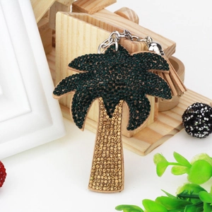 Detail of palm tree keychain with green and gold rhinestones and tassel accent