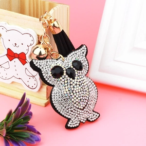 Close-up of owl keychain with white rhinestones, gold bell and black fringe tassel
