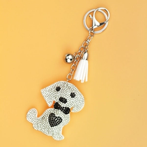 Creative dog keychain with white rhinestones and a soft white tassel on yellow background
