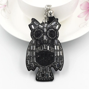 Macro detail of cartoon owl keychain with black rhinestones and elegant tassels