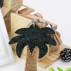 Macro view of palm tree keychain with green rhinestones and brown suede tassel detail