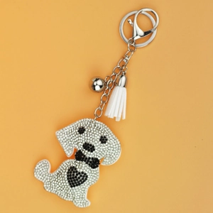 Detailed close-up of a rhinestone dog keychain with a white leather tassel and silver bell