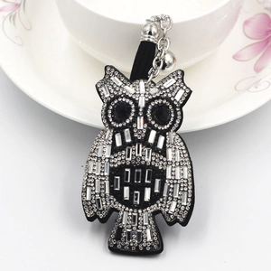 Close-up of owl keychain with silver rhinestones, black tassel and small bell detail