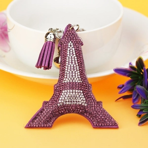 Purple Eiffel Tower keychain with rhinestones, tassels and a bell on yellow background