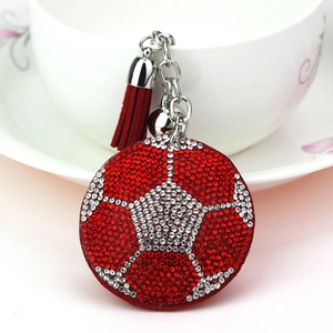 Gros plan d'un porte-clés de football en strass avec glands rouges et cloche argentée