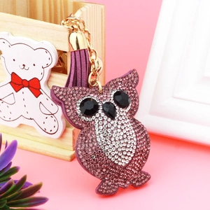 Detail of owl keychain with purple rhinestones, leather tassel, and golden metal clasp