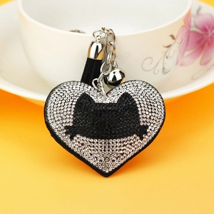 Sparkling rhinestone cat heart keychain with black tassel and bell on yellow backdrop
