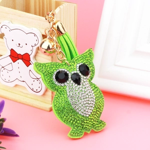 Macro view of crystal owl keychain with green rhinestones and leather tassel detail