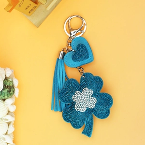 Macro detail of blue faux suede four-leaf clover keychain with rhinestones and tassel