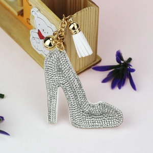 Detailed view of high heel keychain with white rhinestones, golden bell and velvet tassel