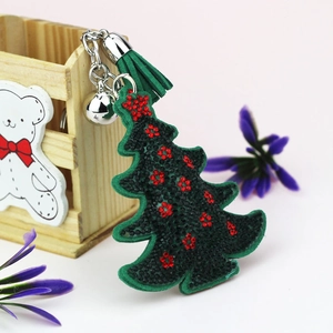 Détail d'un porte-clés sapin de Noël en velours vert avec strass rouges et pompon vert