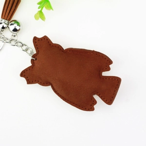 Detailed close-up of brown faux leather owl keychain with metal bell and tassel charm