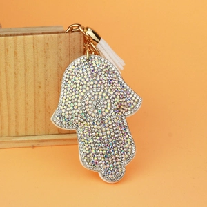 Hamsa Hand keychain with colorful rhinestones and white tassel on orange background