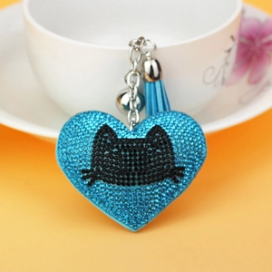 Detail of blue rhinestone heart keychain with cat pattern and silk tassel on cup